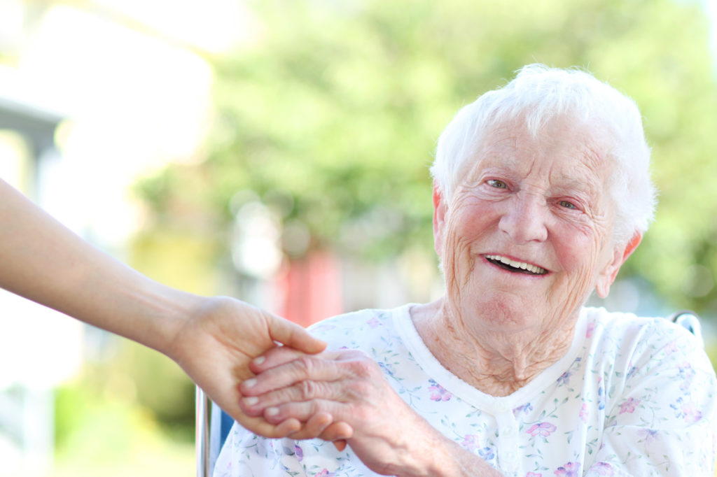 Happy senior woman holding hands with caretaker